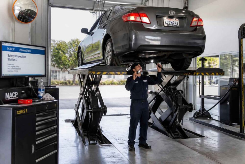 Mechanik ogląda podwozie Toyoty uniesionej na nożycowym podnośniku w warsztacie