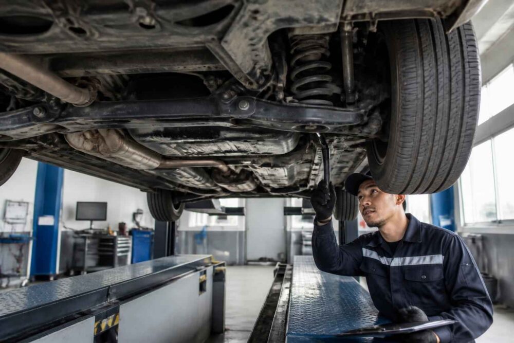 Mechanik ogląda podwozie auta na stanowisku diagnostycznym w warsztacie samochodowym